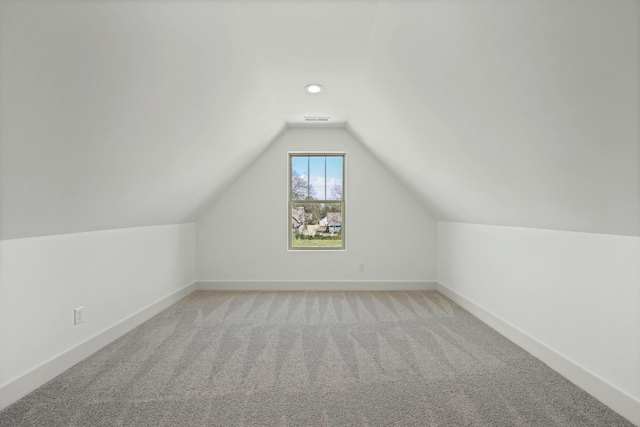 additional living space with lofted ceiling, light colored carpet, visible vents, and baseboards