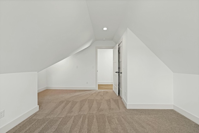 additional living space featuring baseboards, light carpet, and lofted ceiling