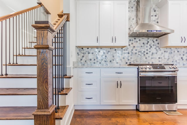 kitchen featuring white cabinets, dark hardwood / wood-style flooring, electric range, and wall chimney range hood