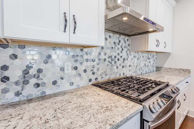 kitchen with white cabinets, stainless steel stove, light stone counters, extractor fan, and decorative backsplash