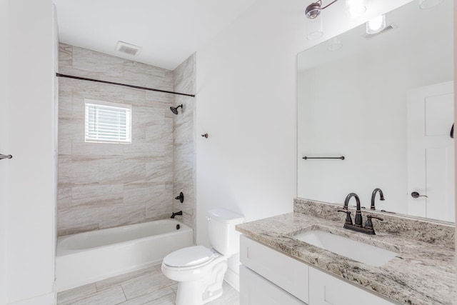 full bathroom featuring tiled shower / bath, vanity, and toilet