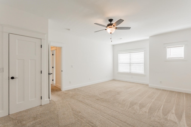 empty room featuring ceiling fan and light carpet