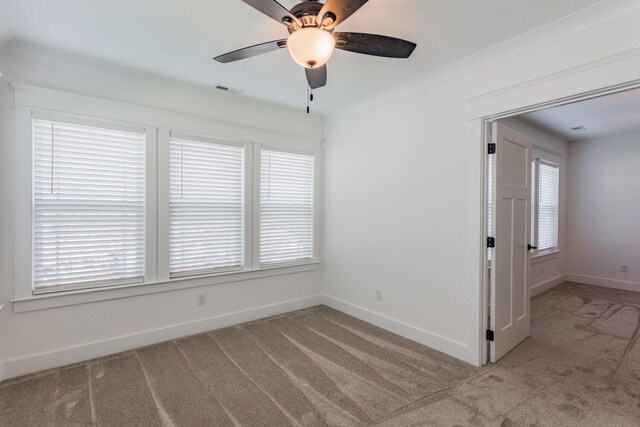 spare room featuring plenty of natural light, ceiling fan, and light carpet