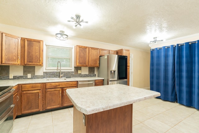 kitchen featuring a textured ceiling, crown molding, a center island, stainless steel appliances, and sink