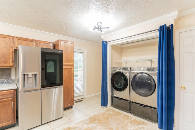 laundry area with a textured ceiling, crown molding, washer and clothes dryer, and light tile patterned floors