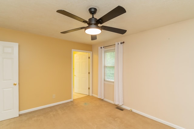 spare room featuring light colored carpet and ceiling fan