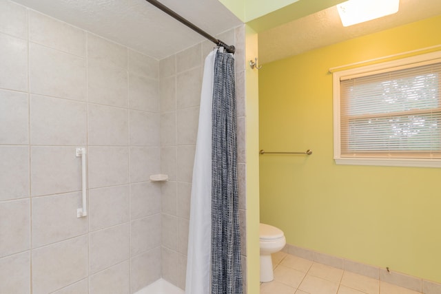 bathroom with a textured ceiling, toilet, curtained shower, and tile patterned flooring