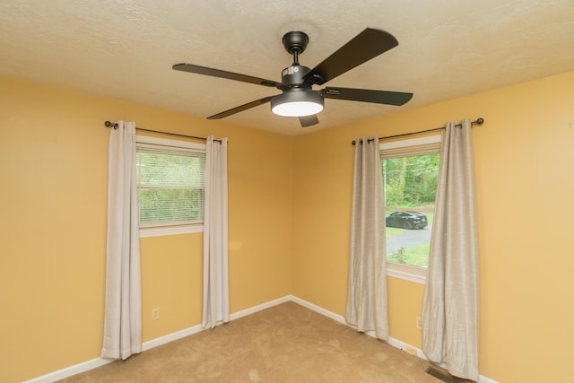 empty room with light carpet, a textured ceiling, and ceiling fan