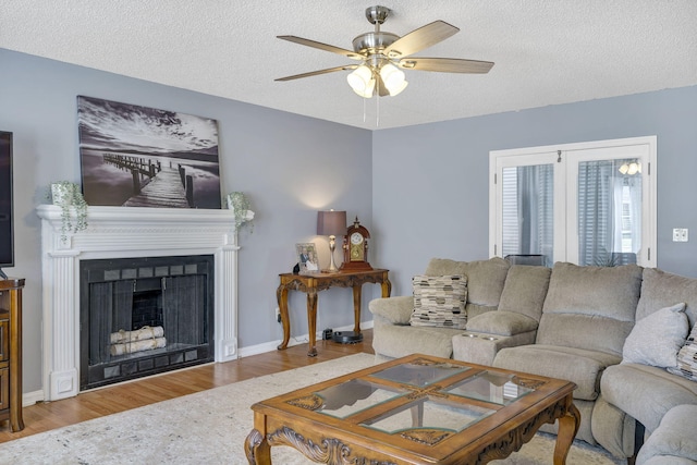 living room featuring light wood-type flooring, a textured ceiling, and ceiling fan