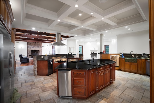 kitchen with a fireplace, dark stone countertops, stainless steel fridge, kitchen peninsula, and a center island with sink