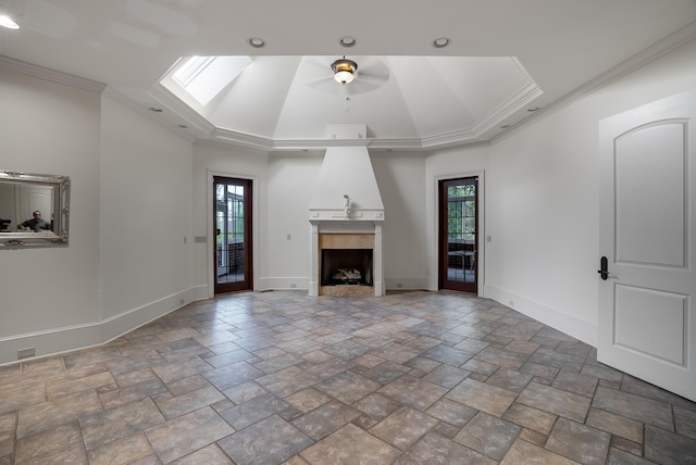 unfurnished living room featuring ornamental molding, a skylight, a tray ceiling, and ceiling fan