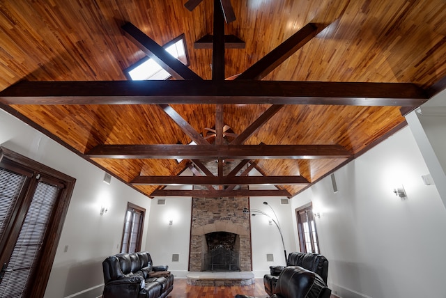 living room featuring ceiling fan, vaulted ceiling with beams, and a fireplace