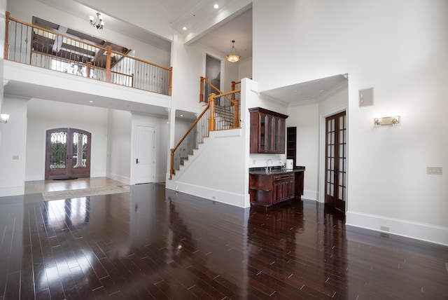 foyer entrance with an inviting chandelier, dark hardwood / wood-style flooring, beam ceiling, ornamental molding, and a towering ceiling