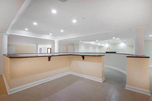 kitchen featuring a breakfast bar, kitchen peninsula, and ornate columns