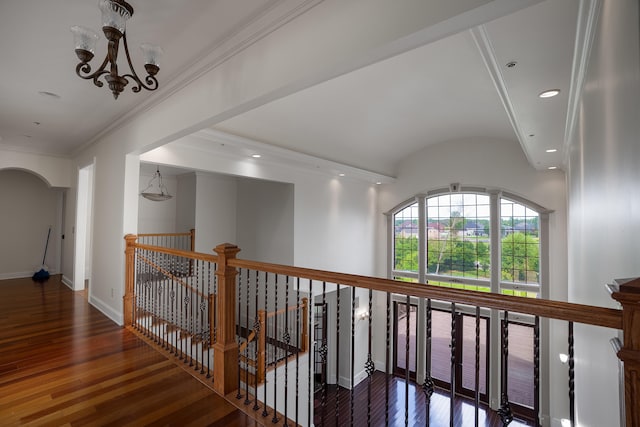 corridor featuring ornamental molding, dark wood-type flooring, and an inviting chandelier