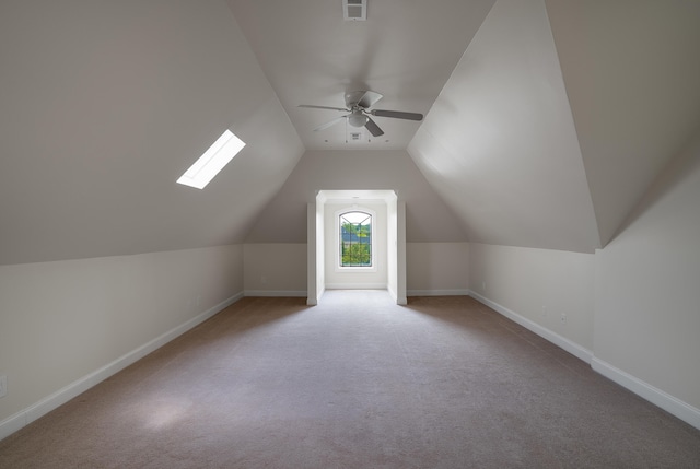 additional living space with carpet flooring, ceiling fan, and lofted ceiling with skylight