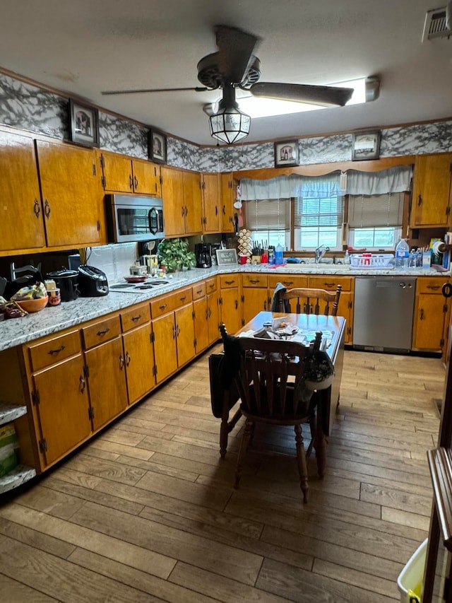 kitchen featuring stainless steel appliances, ceiling fan, and light hardwood / wood-style floors