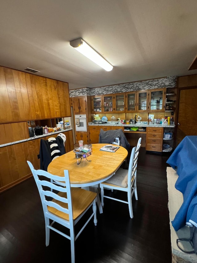 dining space with dark hardwood / wood-style floors and wooden walls