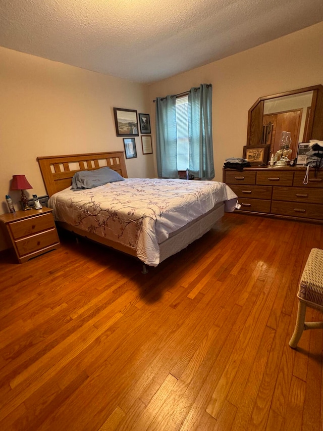 bedroom with a textured ceiling and hardwood / wood-style flooring