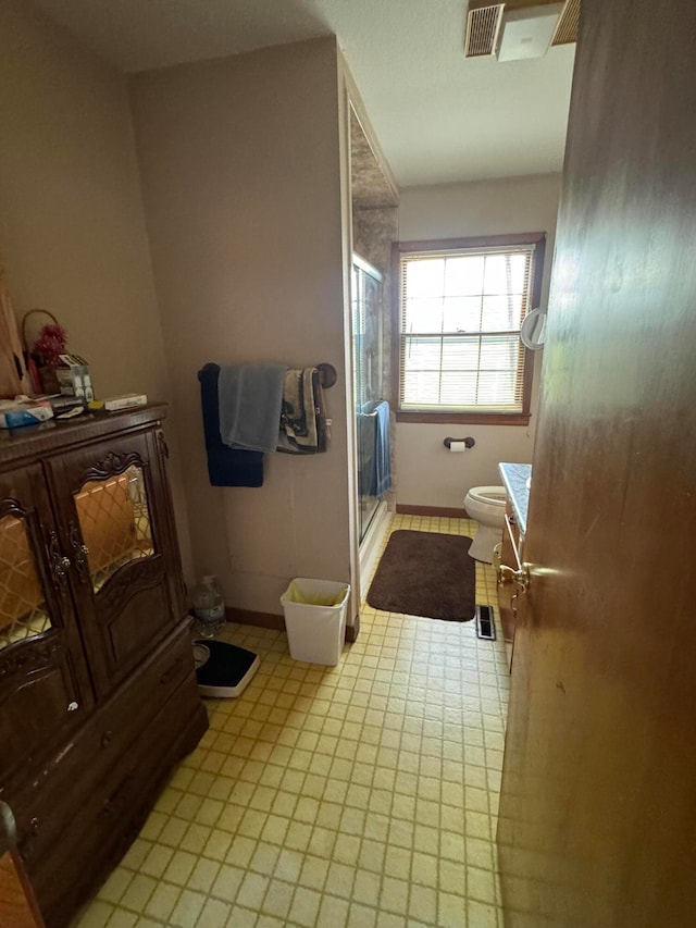 bathroom featuring toilet and a shower with shower door