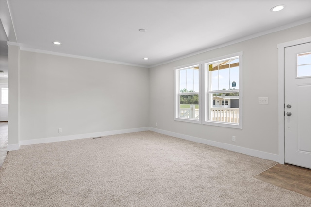 carpeted entryway with a healthy amount of sunlight and crown molding