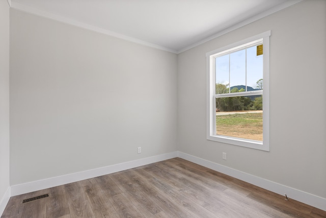 empty room featuring ornamental molding and light hardwood / wood-style flooring