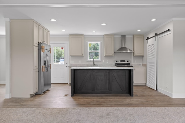 kitchen with wall chimney exhaust hood, a barn door, light hardwood / wood-style flooring, ornamental molding, and appliances with stainless steel finishes