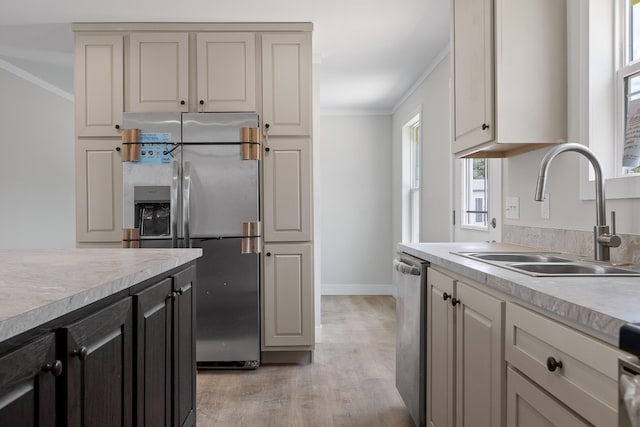 kitchen with stainless steel appliances, light wood-type flooring, sink, and crown molding