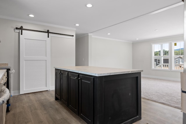 kitchen with a barn door, ornamental molding, light hardwood / wood-style flooring, and a center island