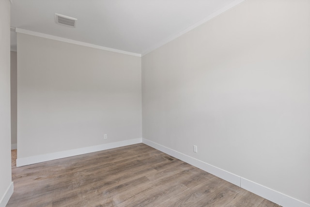 spare room featuring ornamental molding and light hardwood / wood-style floors