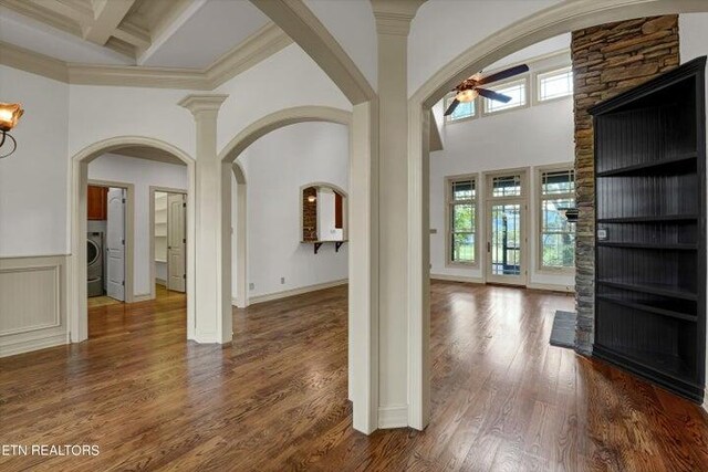 entrance foyer with beamed ceiling, dark hardwood / wood-style floors, ceiling fan, a stone fireplace, and a towering ceiling