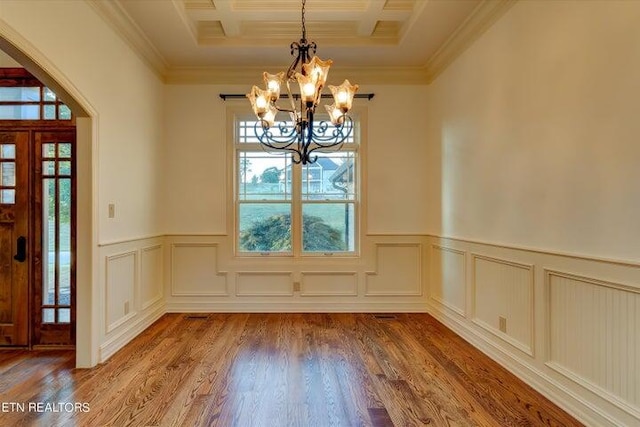 unfurnished dining area featuring crown molding, coffered ceiling, hardwood / wood-style floors, and a notable chandelier