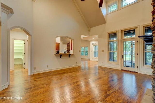 unfurnished living room with hardwood / wood-style floors, high vaulted ceiling, and ceiling fan