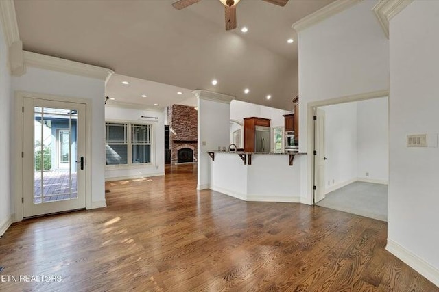 unfurnished living room with a high ceiling, ceiling fan, a fireplace, and dark hardwood / wood-style flooring