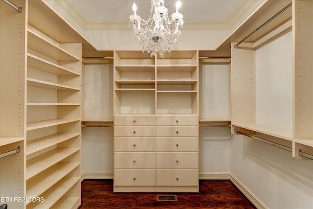 spacious closet with dark wood-type flooring and a chandelier