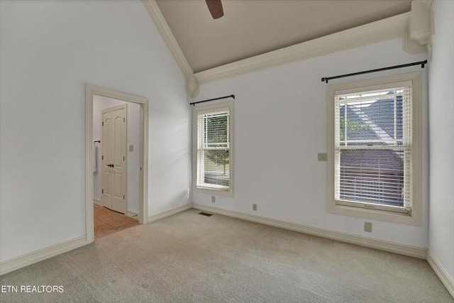 empty room with lofted ceiling, light colored carpet, crown molding, and ceiling fan