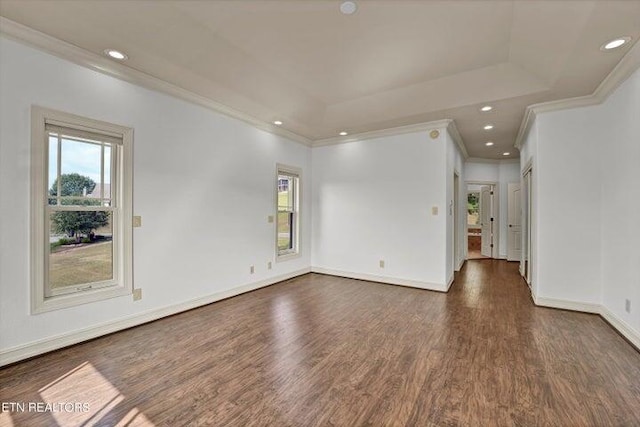 empty room featuring a tray ceiling, dark hardwood / wood-style flooring, and ornamental molding