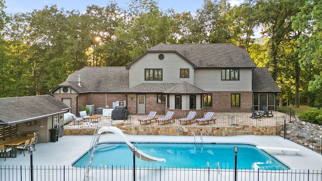 view of pool featuring grilling area, a diving board, a water slide, and a patio area