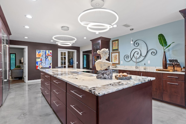 kitchen featuring a kitchen island, decorative light fixtures, a chandelier, black electric stovetop, and light stone countertops