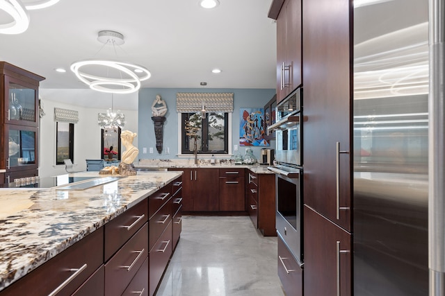 kitchen with light stone countertops, appliances with stainless steel finishes, hanging light fixtures, and a chandelier