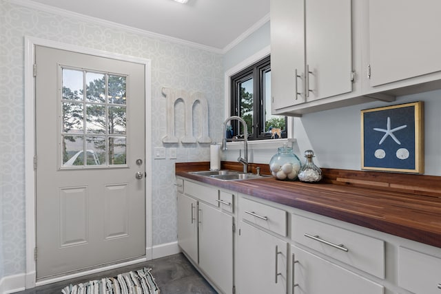 kitchen with wooden counters, sink, white cabinetry, and a wealth of natural light