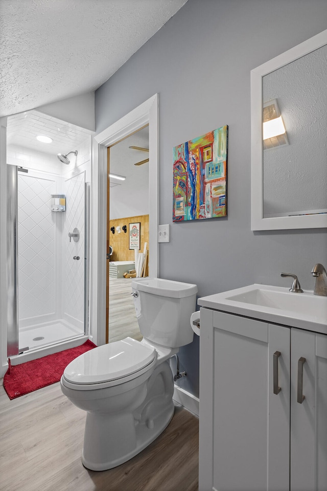 bathroom featuring vanity, tiled shower, a textured ceiling, hardwood / wood-style flooring, and toilet