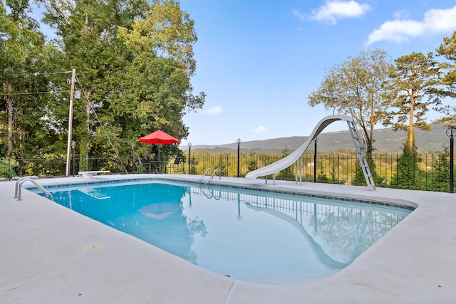 view of swimming pool featuring a mountain view, a diving board, and a water slide