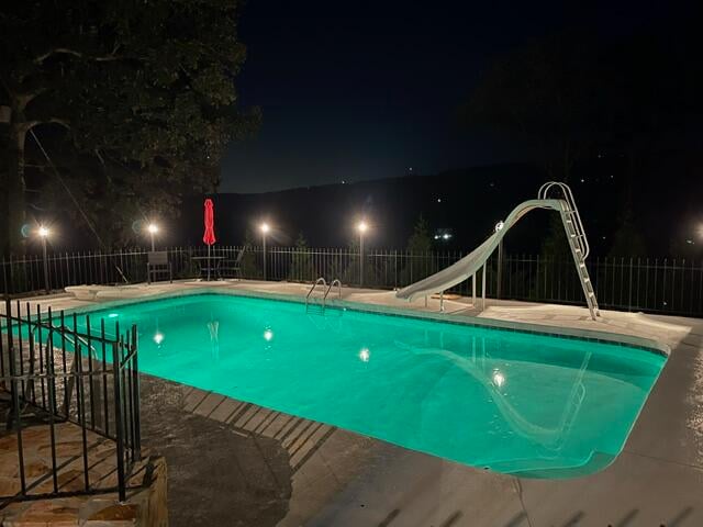 pool at night featuring a water slide