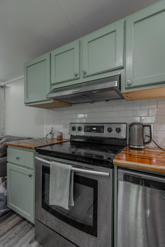 kitchen with green cabinets, hardwood / wood-style floors, stainless steel appliances, and butcher block counters