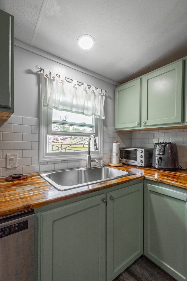 kitchen featuring dishwasher, green cabinetry, and butcher block counters