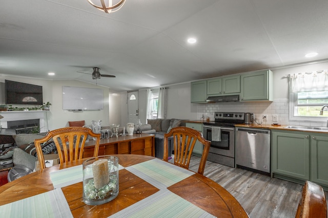 dining space featuring light wood-type flooring, ceiling fan, vaulted ceiling, and sink