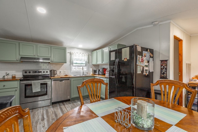 dining area featuring lofted ceiling, ornamental molding, sink, and light hardwood / wood-style floors