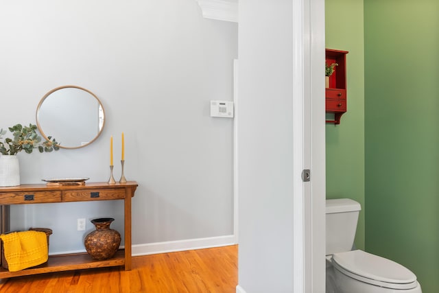 bathroom featuring wood-type flooring, crown molding, and toilet