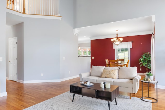 living room with crown molding, a high ceiling, an inviting chandelier, and hardwood / wood-style flooring